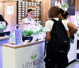 Une exposante échange avec des visiteurs sur un stand dédié au potager d’intérieur Véritable.