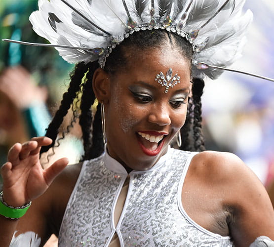 jeune femme en train de danser pendant le Festival Tropiques en Fête, vêtue d'un costume blanc, de strass, de paillettes et de plumes