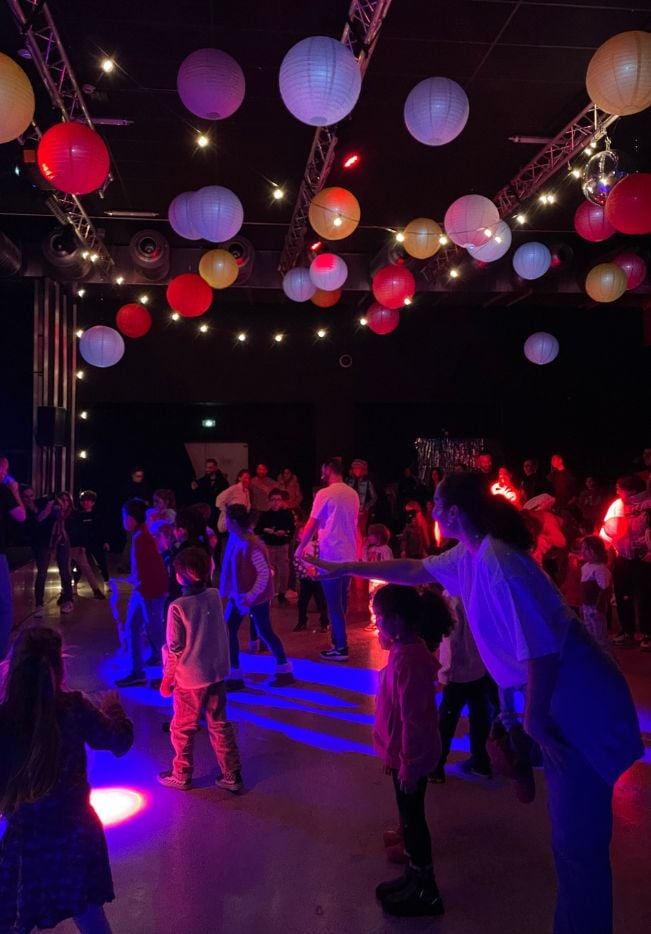 enfants dans une salle des fêtes décorée avec des ballons au plafond profitant d'une boum