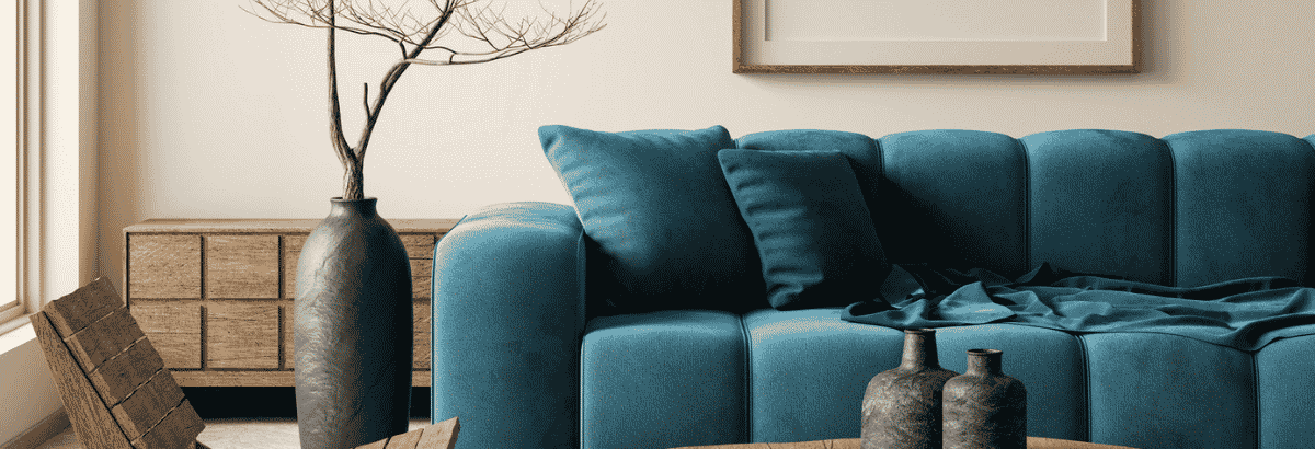 Canapé en tissu bleu avec coussins assortis, dans un salon aux tons bois et beige, accompagné d'un vase décoratif et d'une table basse avec des objets en céramique.