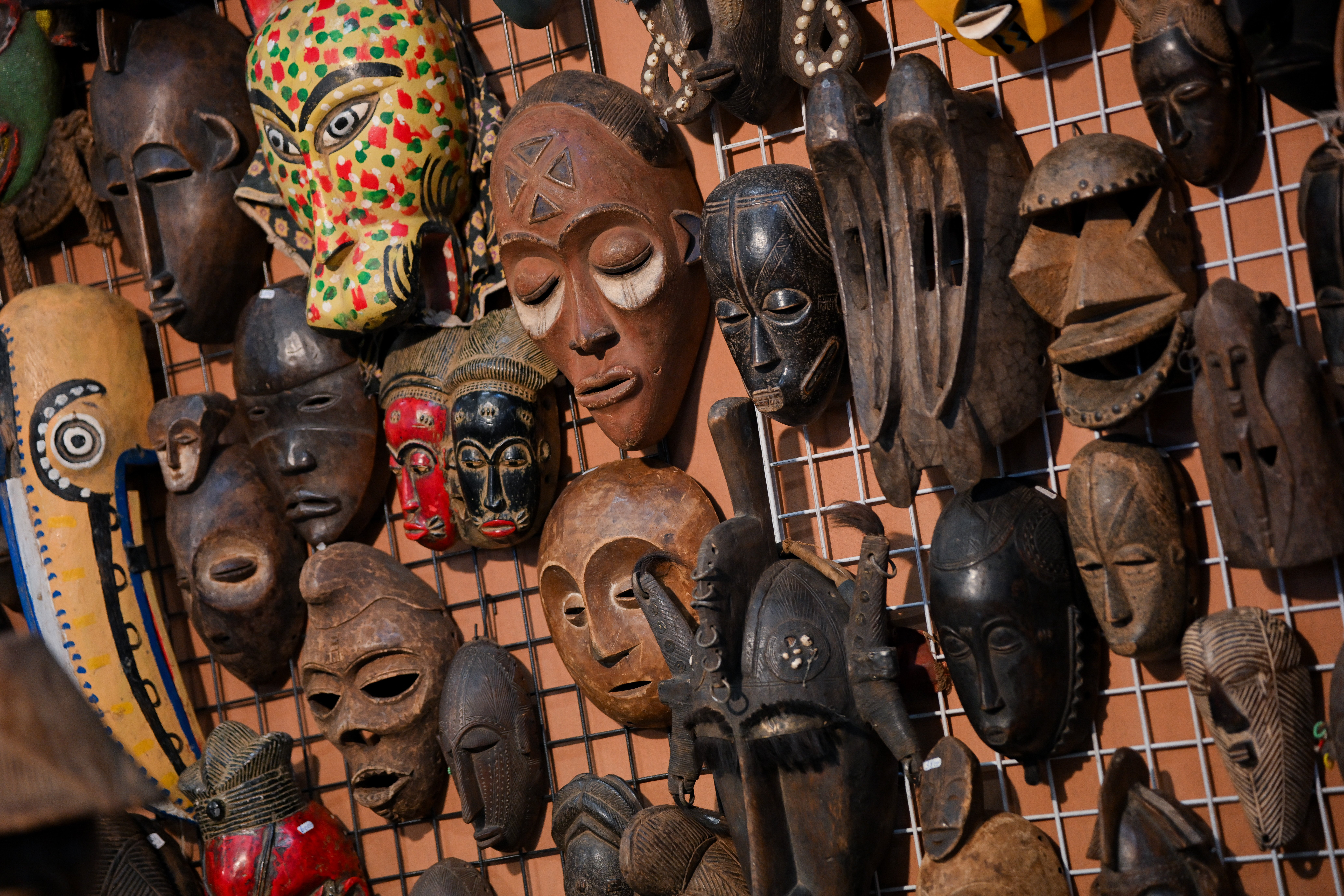 Collection de masques africains traditionnels en bois exposés sur un mur dans une boutique d’artisanat