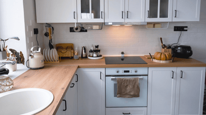 Cuisine fonctionnelle blanche et bois avec plan de travail chaleureux, crédence sobre et rangements optimisés pour un style moderne et convivial.