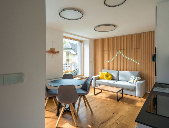 Intérieur moderne avec salon et salle à manger, canapé, table ronde et mur en bois décoratif