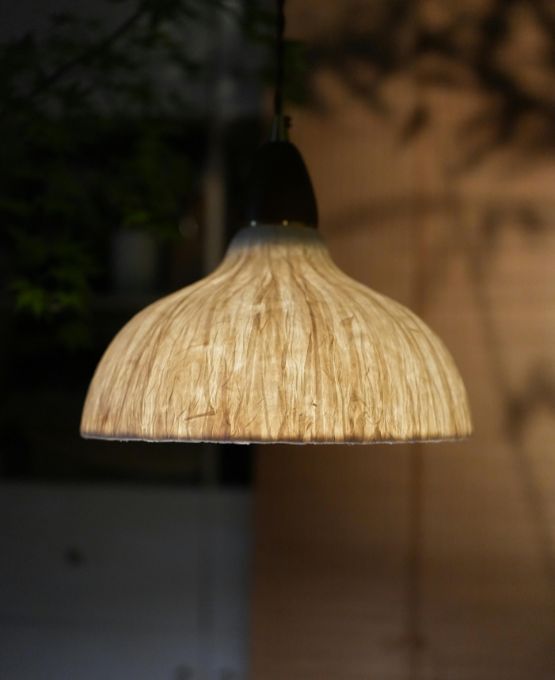Suspension minimaliste en bois éclairant un espace intérieur avec une lumière douce.