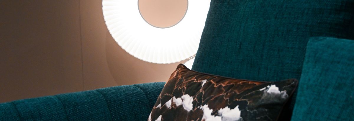 Canapé bleu avec coussin design et lampe ronde moderne à côté.