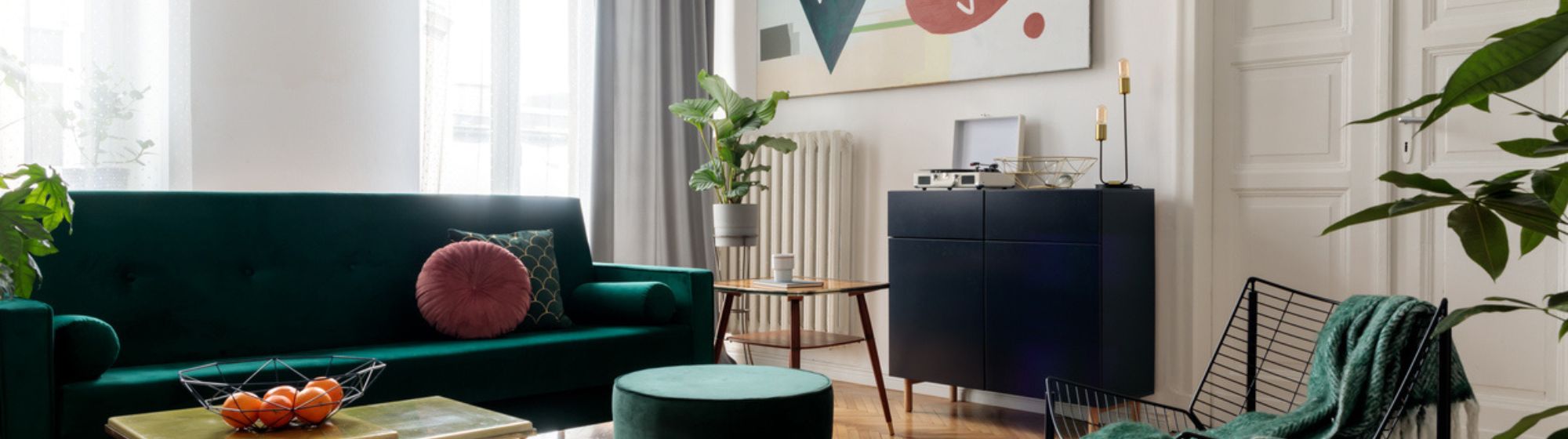 Salon moderne avec canapé vert, fauteuil design, table basse et œuvre murale colorée, intérieur lumineux et décoré