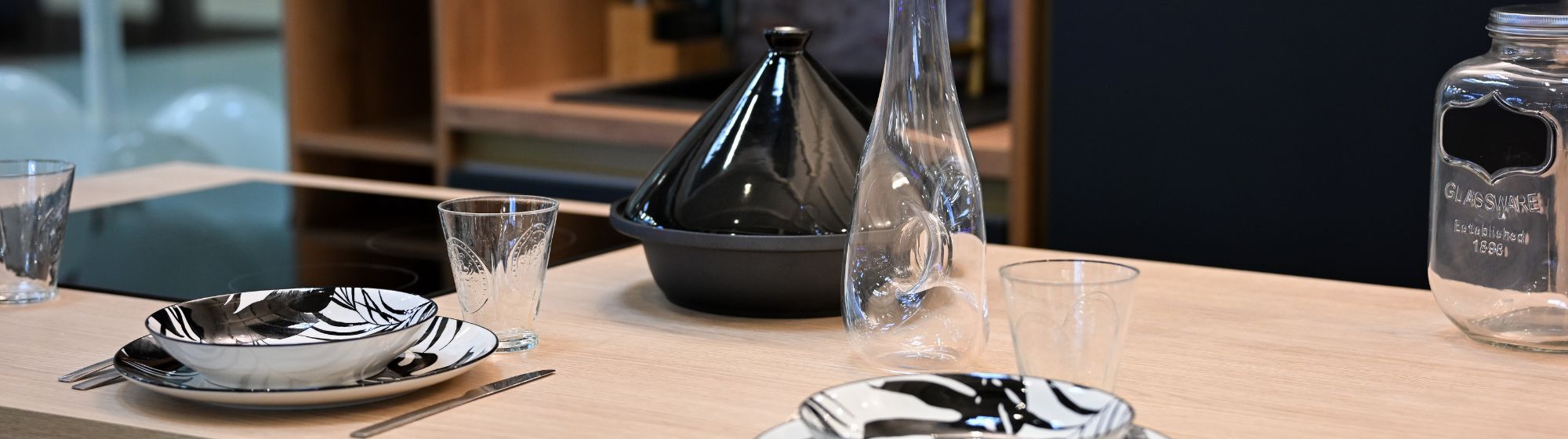 Table moderne dressée avec assiettes, verres et carafe, dans une cuisine contemporaine au design épuré