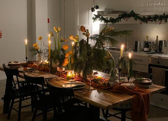 Table en bois dressée avec bougies, fleurs et plats, ambiance chaleureuse et intime pour un dîner convivial en intérieur