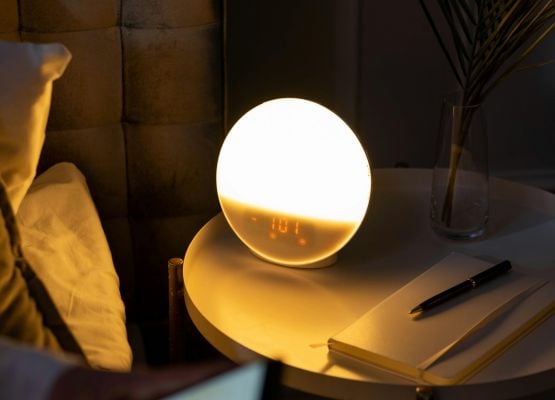 Lampe de chevet lumineuse avec affichage digital sur table de nuit, ambiance chaleureuse dans une chambre moderne