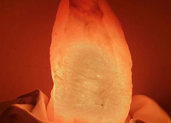 Lampe en pierre de sel diffusant une lumière chaude et apaisante dans une ambiance cosy.